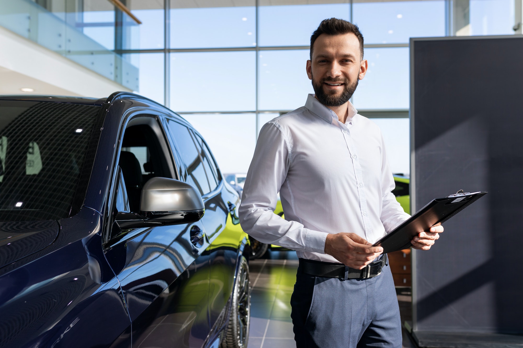 insurance company employee next to a new car in a car dealership center