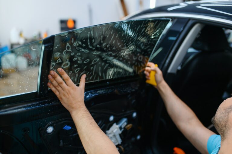 Worker installs wetted car tinting, tuning service