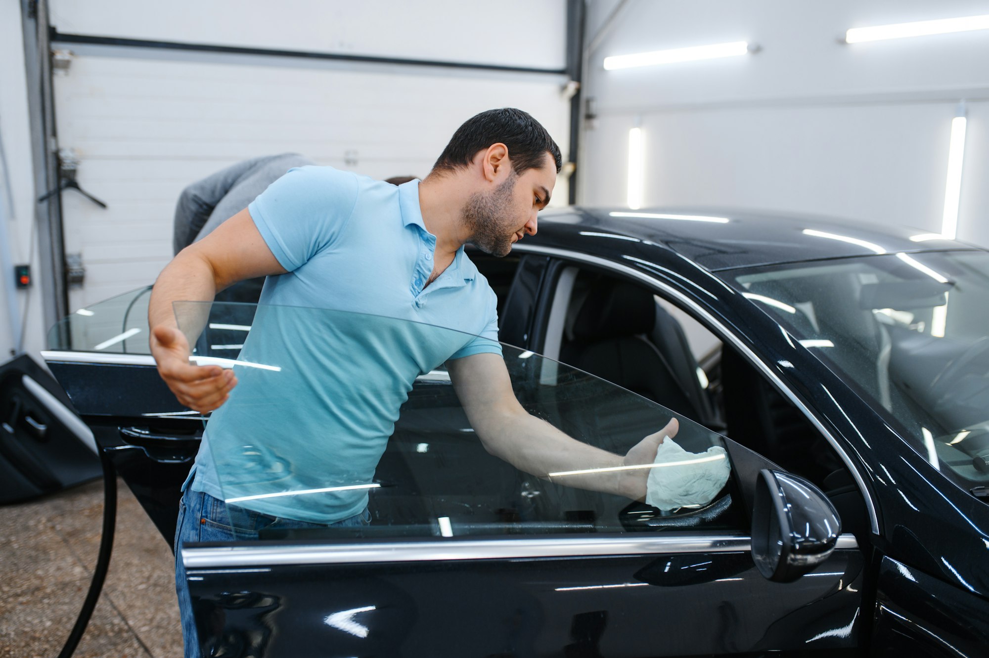 Male worker cleans car for tinting, tuning service